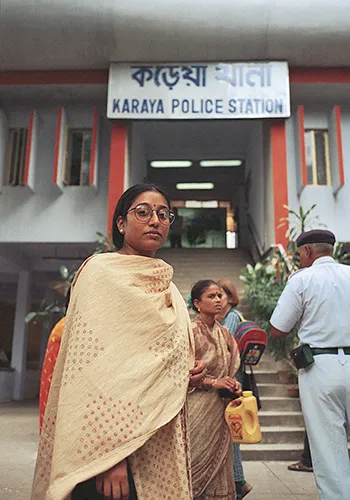 A woman in Kolkata, India, wrapped in a Sari, standing outside of a police station.