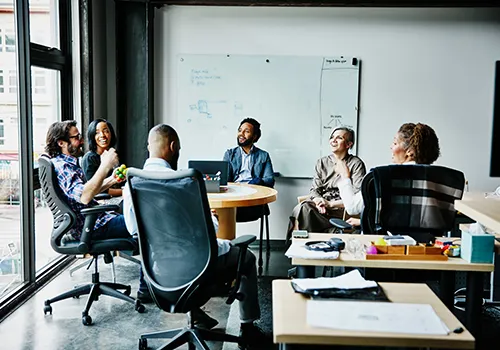A group of six diverse individuals meeting together in a business setting.