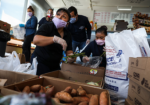 Various foodservice workers prepping meals and processing vegetables in a community kitchen