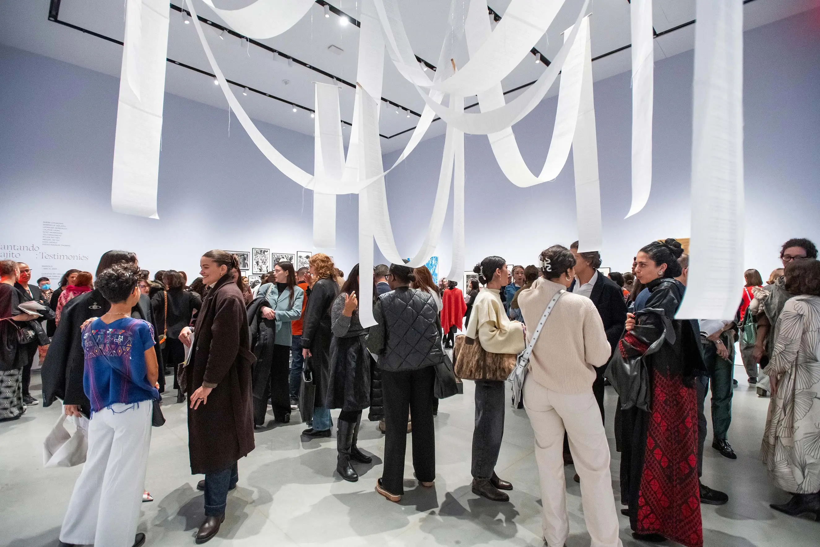 A room filled with people and white paper streamers hanging from the ceiling.