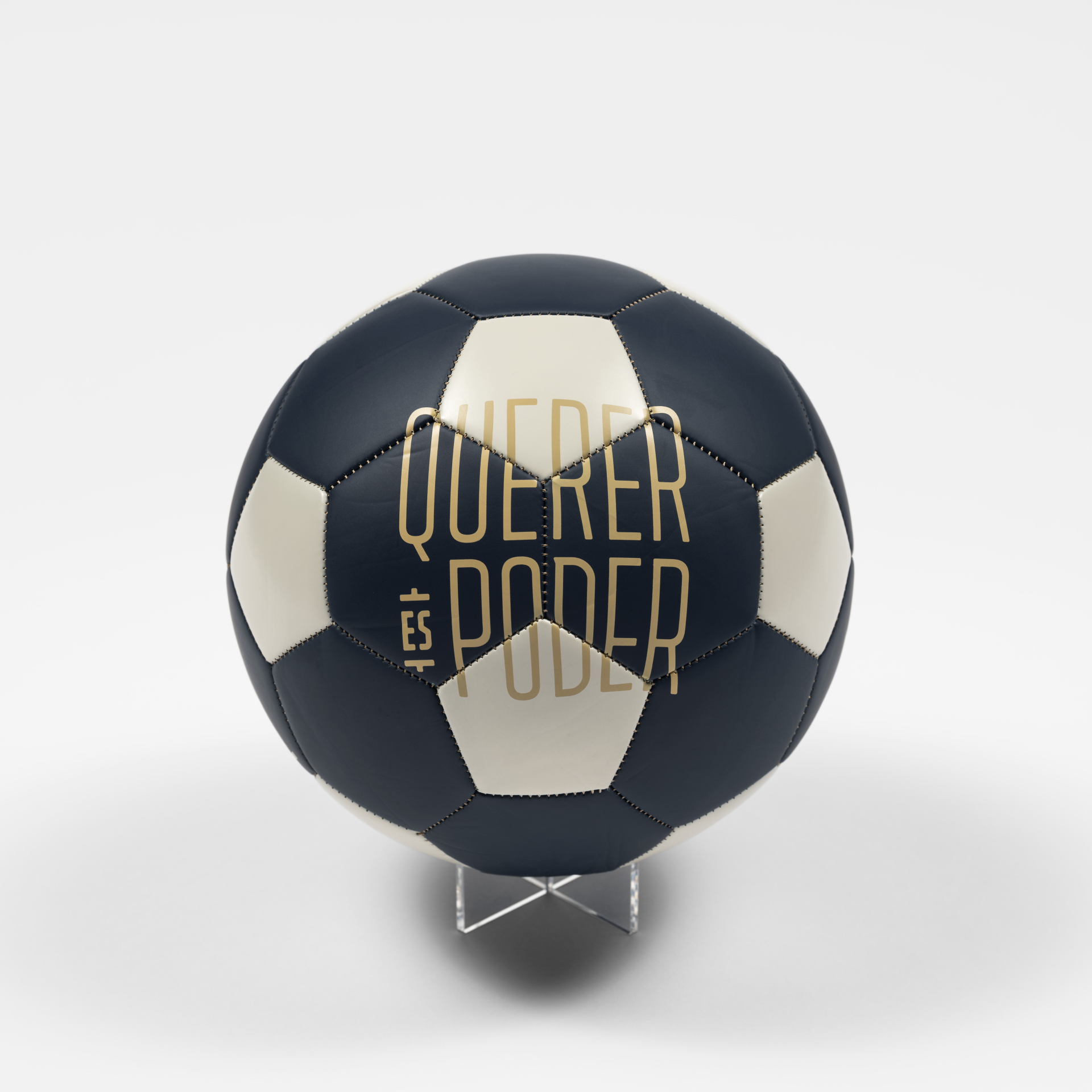 A black soccer ball with white accents and the text, “Querer es Poder.”