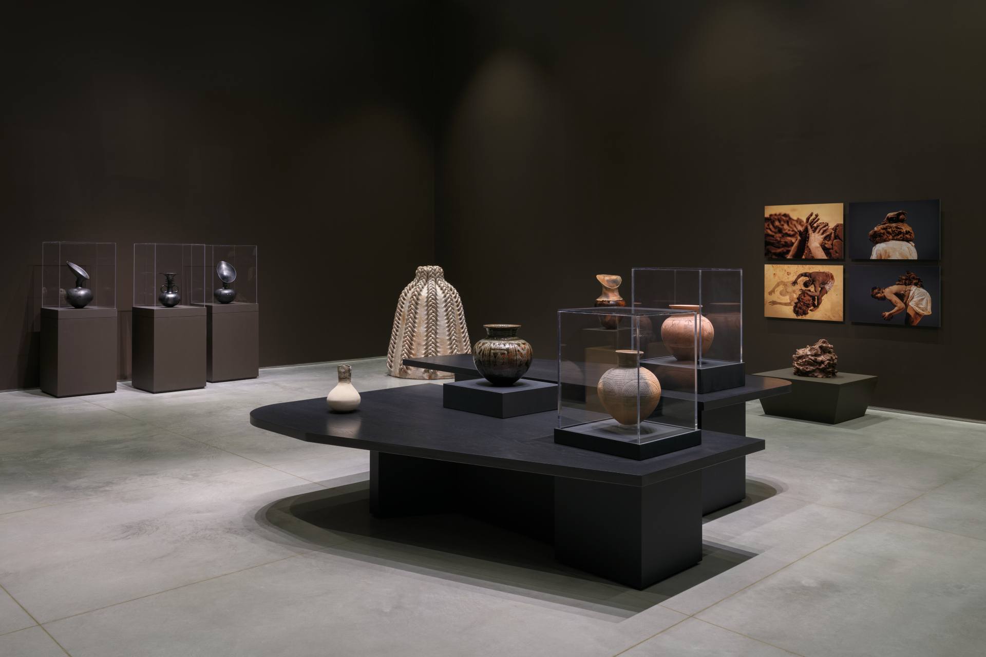 An installation view of a gallery exhibition featuring various ceramic sculptures and clay pots that differ in size, texture and color.