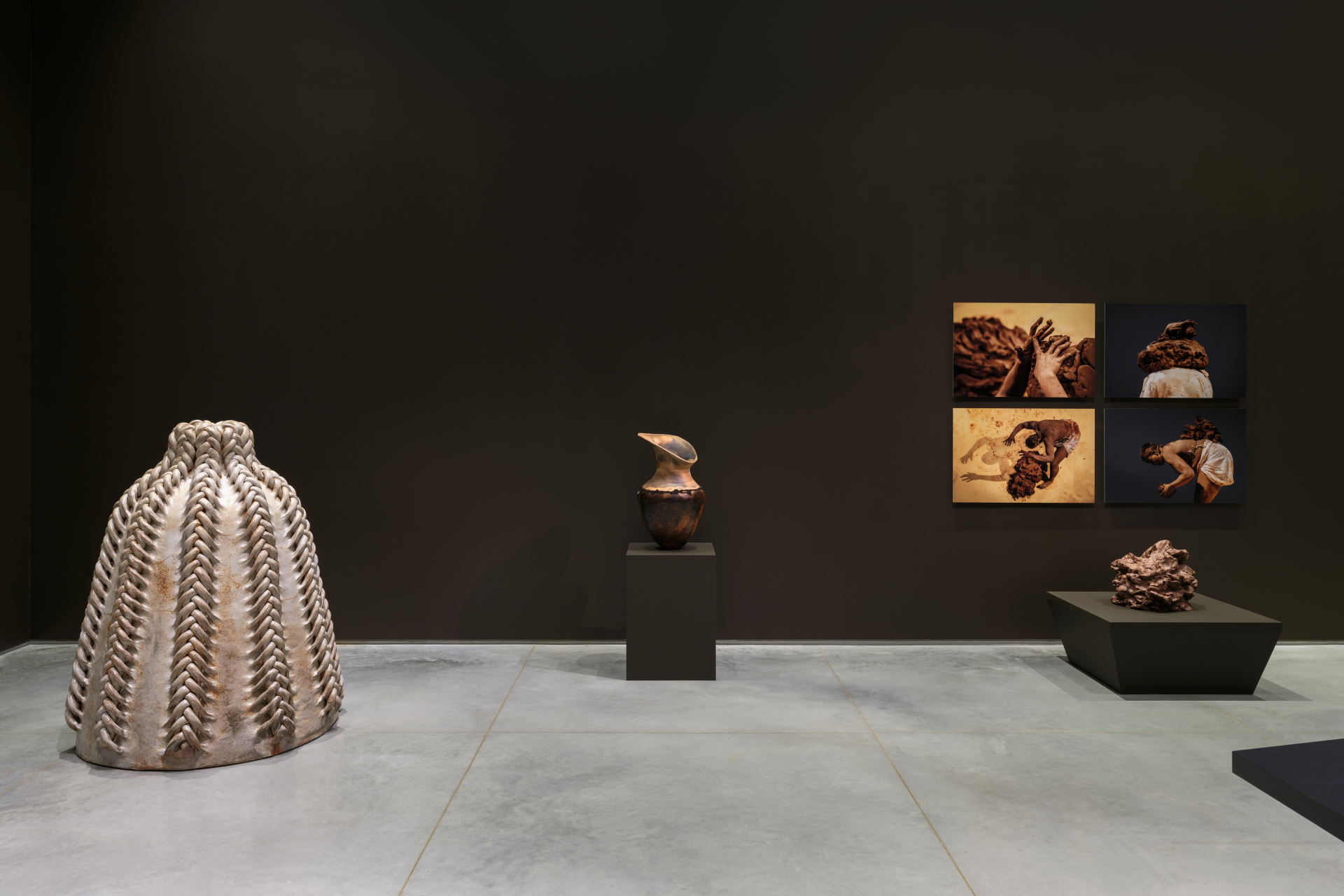 Various artworks relating to clay including a five-feet tall sculpture, a vase, a mound of clay, and four performance photos.